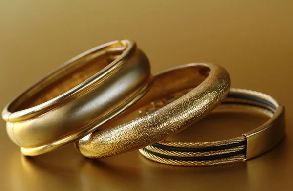 Gold jewelry, bracelets on gold background