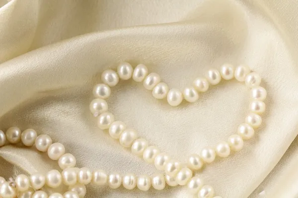 Pearl necklace in the shape of heart on silk fabric