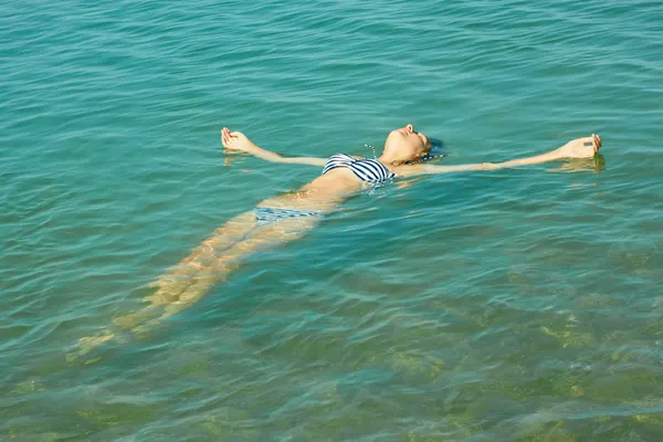 Teen girl lying on the sea water surface