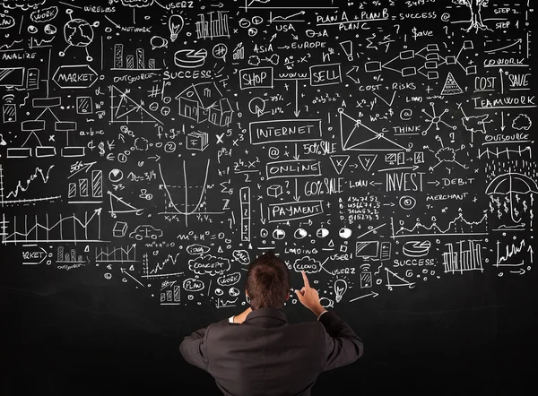 Businessman standing in front of drawn charts on a blackboard