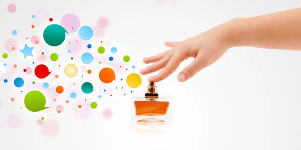 Woman hands spraying colorful bubbles from beautiful perfume bottle