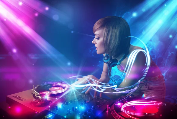 Energetic Dj girl mixing music with powerful light effects