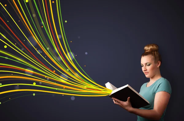 Pretty young woman reading a book while colorful lines are comin