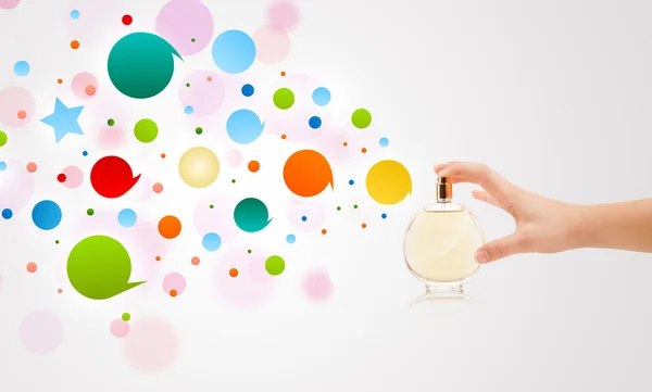 Hands spraying colorful bubbles from beautiful perfume bottle
