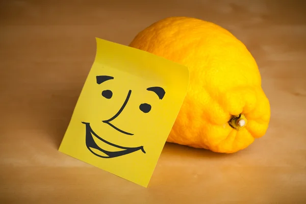 Post-it note with smiley face sticked on a lemon