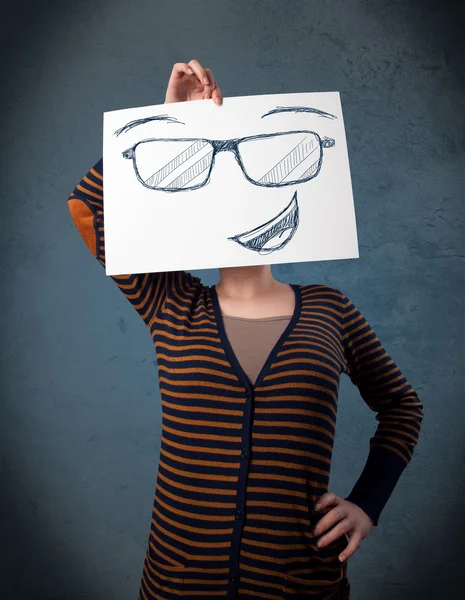 Woman holding a paper with smiley face in front of her head