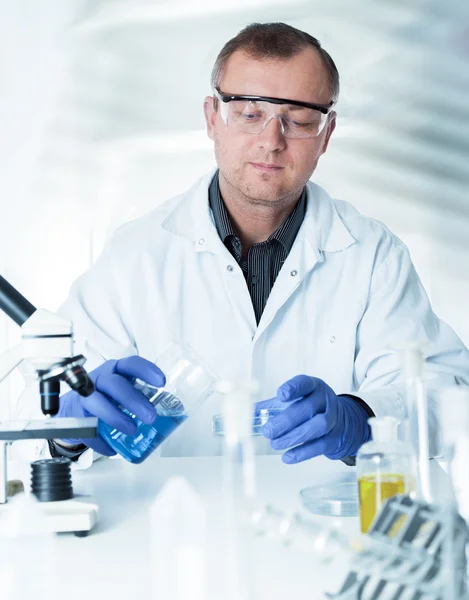 Scientist working in the lab , examines a with liquid