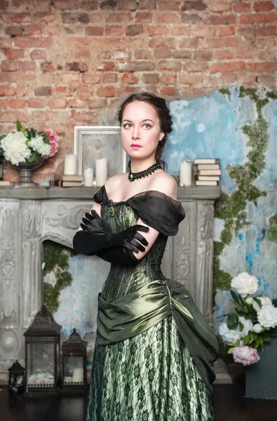 Beautiful woman in medieval dress near fireplace