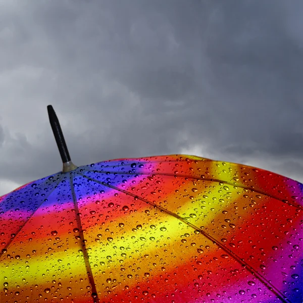Colorful umbrella top with raindrops and heavy clouds