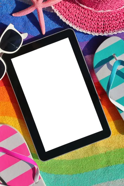 Tablet with blank screen on beach towel with accessories