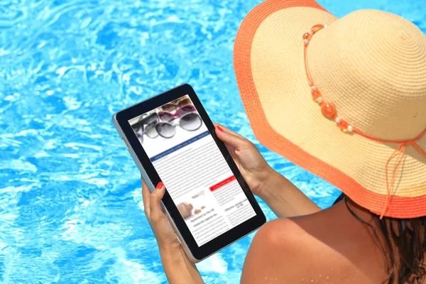 Woman holding tablet computer in the pool