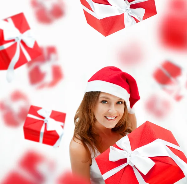 Young woman holding gift box wearing santa claus hat. Many gift