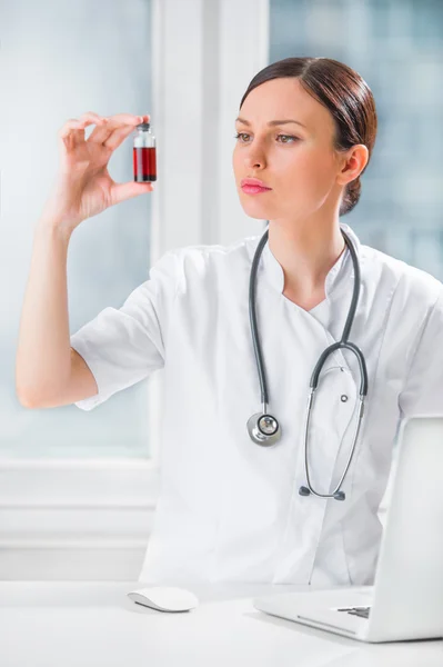 Portrait of pretty female laboratory assistant analyzing a blood