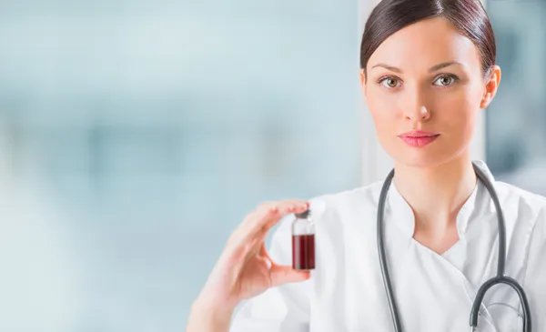 Portrait of pretty female laboratory assistant analyzing a blood