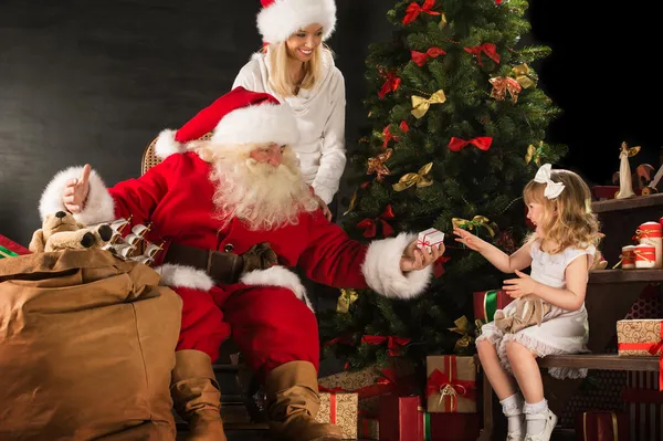 Photo of cute girl and her mother and Santa Claus at home