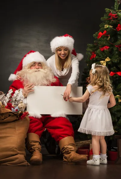 Santa Claus holding white blank sign with family