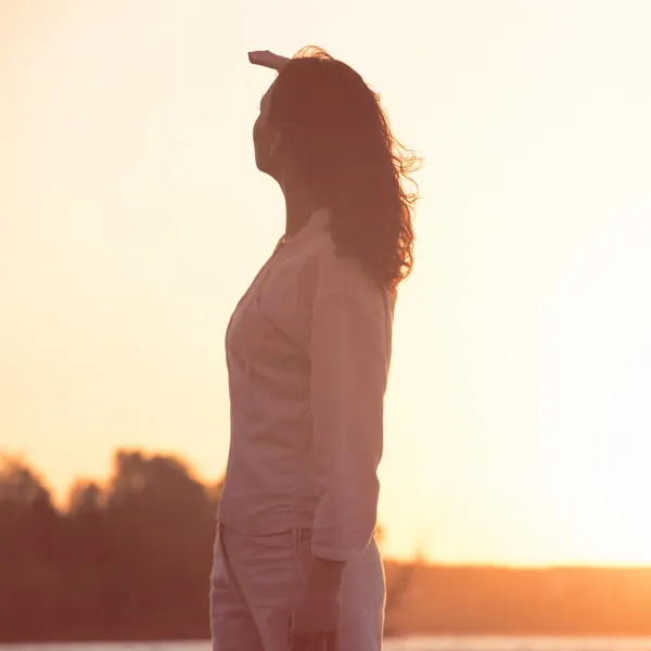 Young and beautiful woman in sunset light looking far away