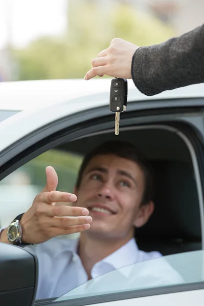 Salesman handing over keys car to businessman