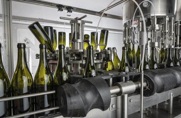 Italy, Sicily, wine bottles being washed and filled with wine by an industrial machine in a wine factory