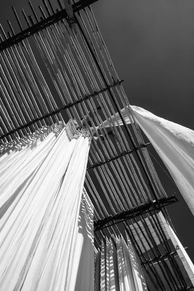 Indian man hanging cotton clothes to dry under the sun