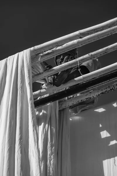 Indian man hanging cotton clothes to dry under the sun