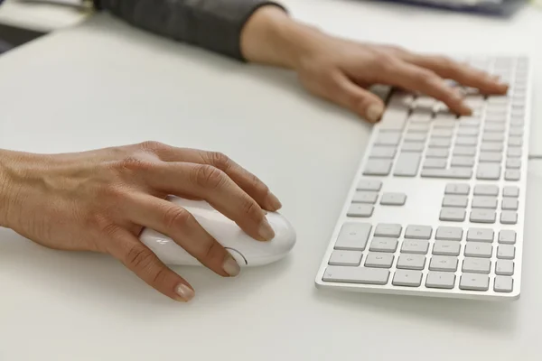 Female hands on a computer\'s keyboard and mouse