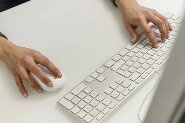Female hands on a computer's keyboard and mouse