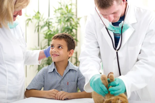 Boy comforting veterinarian, while others veterinarian checks a