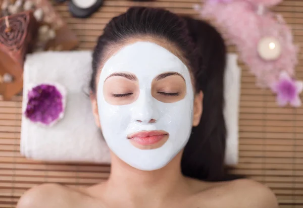 Spa therapy for young woman having facial mask at beauty salon