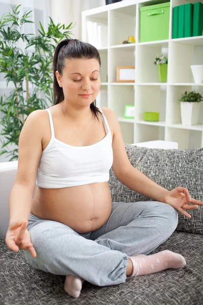 Pregnant woman relax doing yoga, sitting in lotus position,at ho