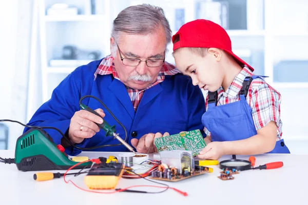 Grandfather explaining to grandchild how soldering works