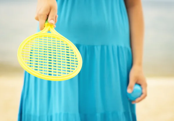 Woman in blue dress playing tennis on the beach