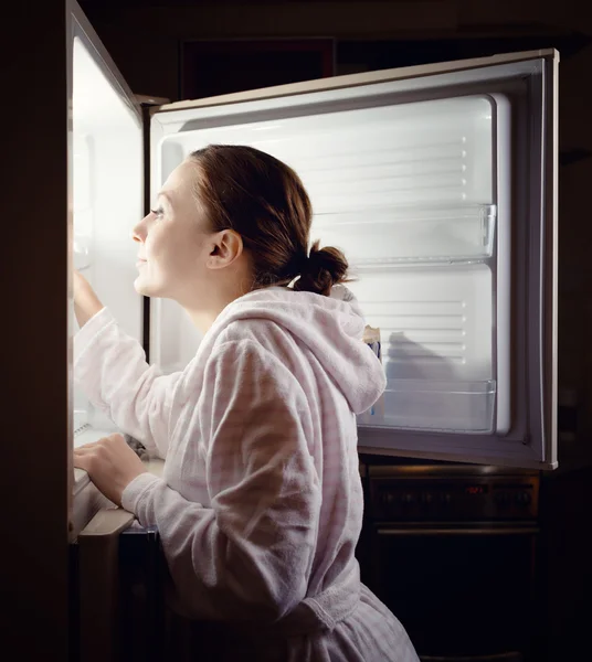 Young woman looking for some snack in fridge late at night
