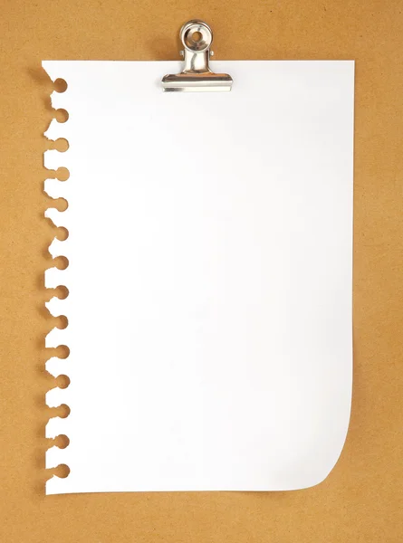 Blank note paper on cardboard background with clip
