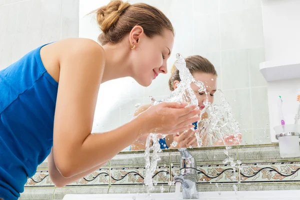 Young woman washing her face with clean water