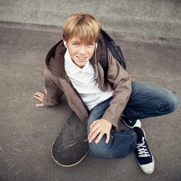 School teen sits on skateboard near school