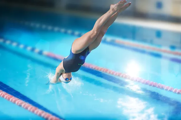 Female swimmer jumping into swimming pool