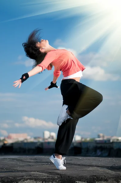Woman dancing hip hop over blue sky and sun