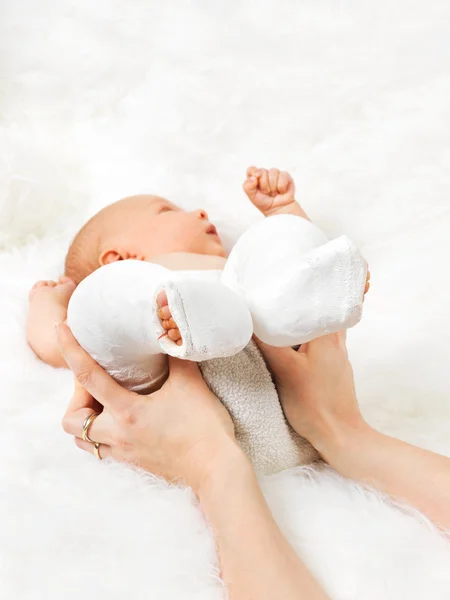 Mother holding newborn baby's legs wrapped in bandage