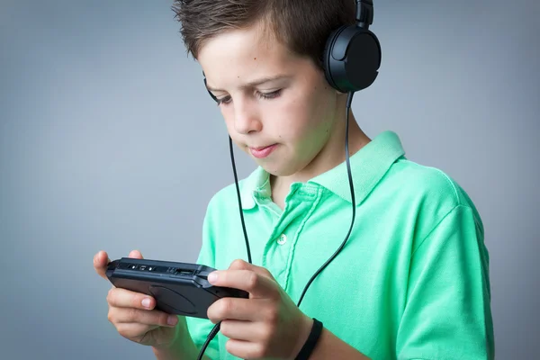 Boy playing game console against grey background