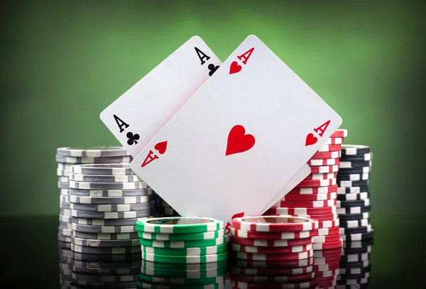 Poker chips and playing cards on green background