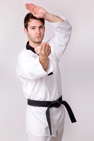 Young man practicing martial arts over grey background