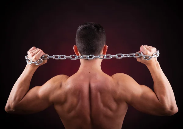 Strong athletic man back on dark background