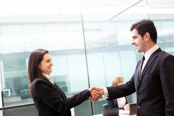 Business handshake at modern office with bussiness on bac