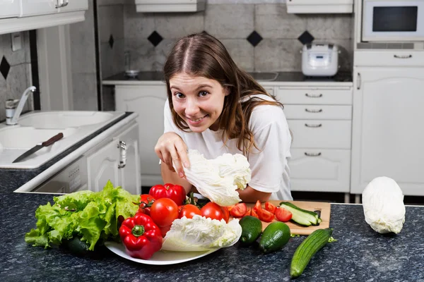 Young female cook making a fresh salad with organic vegetables