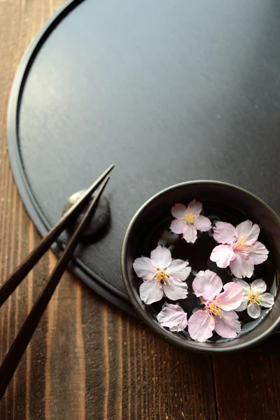 Small bowl of cherry blossoms on black tray
