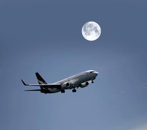 Airplane in the night sky and moon