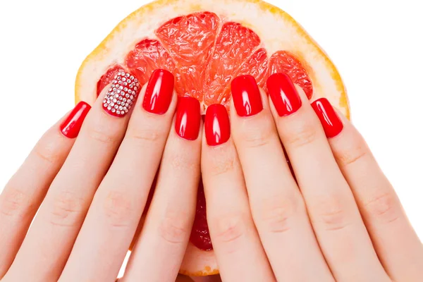 Hands with red nails lie on grapefruit