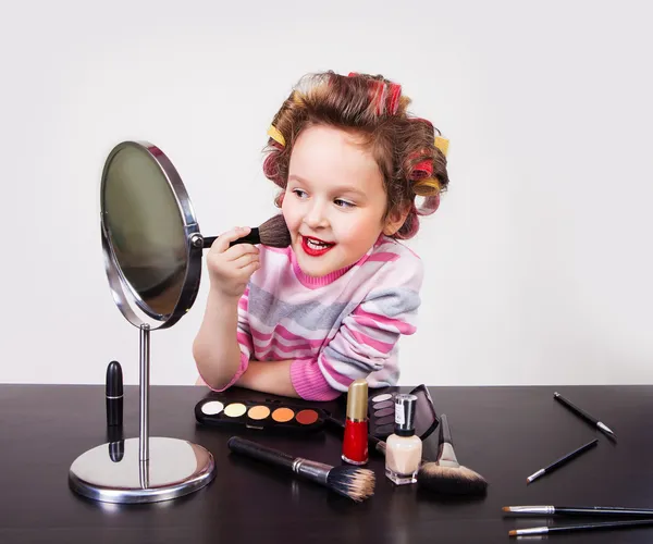 Cute smiling little girl making makeup