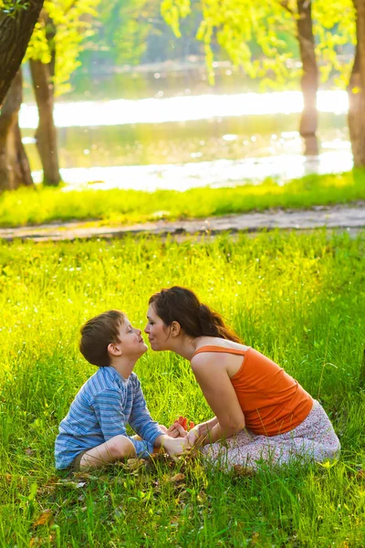 Mom and son woman child sitting on grass kissing sunset Roma